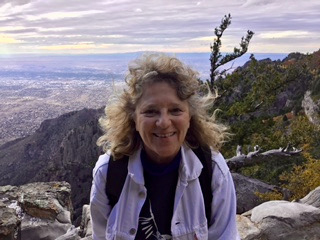 Photo of Katie hiking, smiling, with mountains in the background.