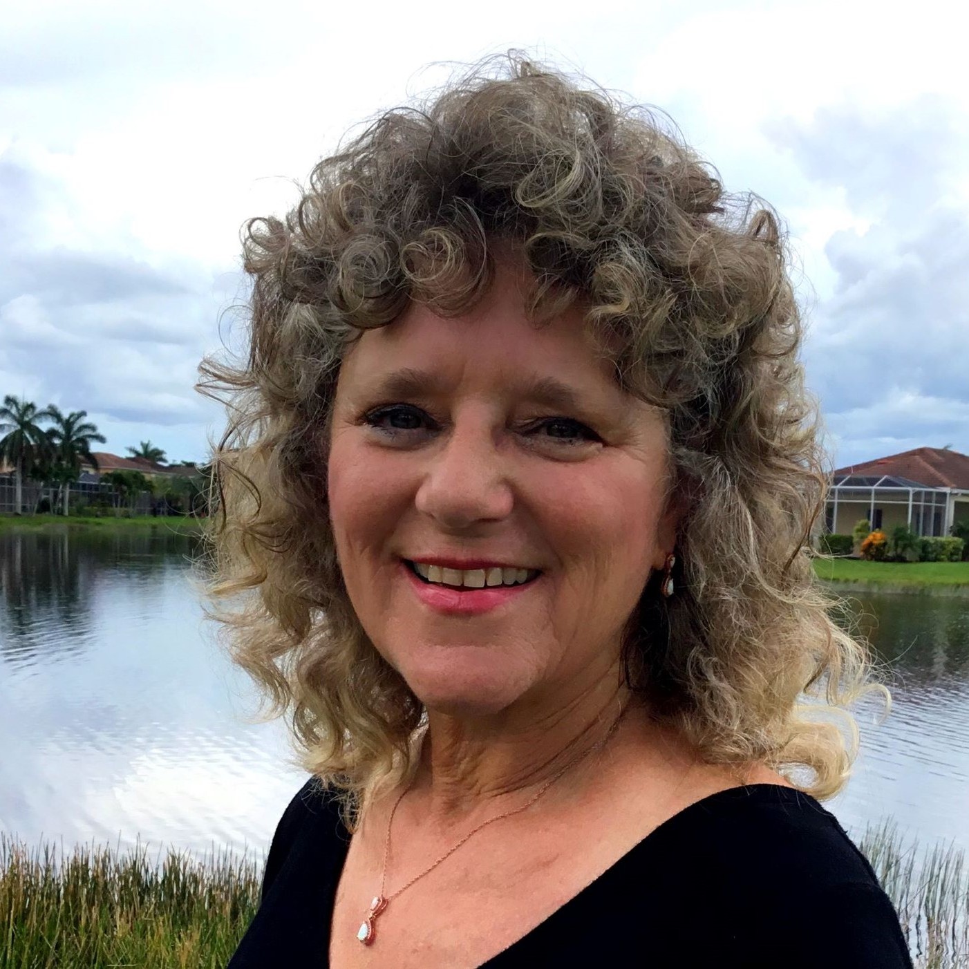 Headshot of Katie Blum-Katz smiling, with a lake and homes in the background.